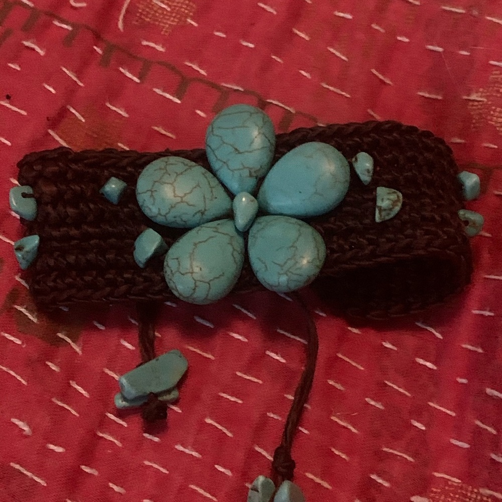 Turquoise bracelet with brown soft twine .